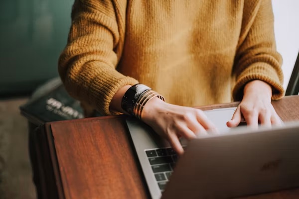 Woman working on a laptop, bangles on her wrist